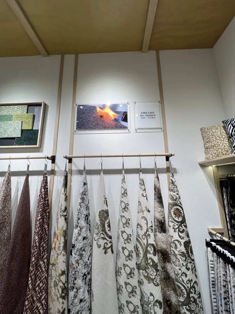 Flame-test photo and FIRE SAFE BY DESIGN sign on the Huaming booth wall