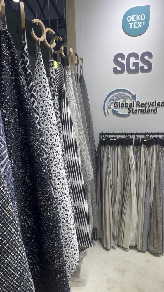 Swatch wall beside OEKO-TEX, SGS and GRS certification marks, Huaming booth (video still)