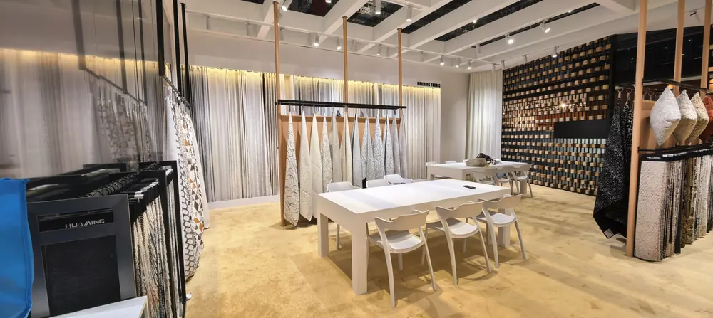 Light-wood interior of the Huaming Fabric booth with hanging fabric swatches, Shanghai 2026