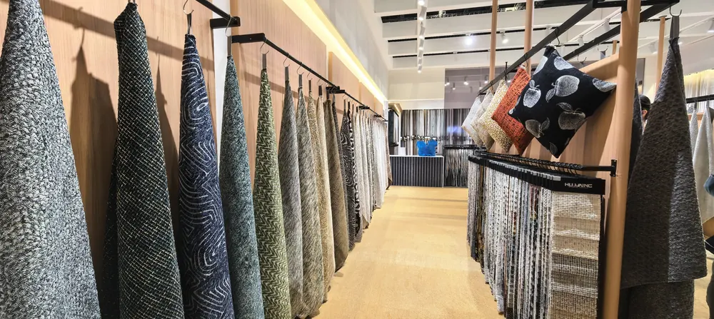 Dark-tone textured upholstery fabrics on the Huaming swatch rail, Shanghai 2026